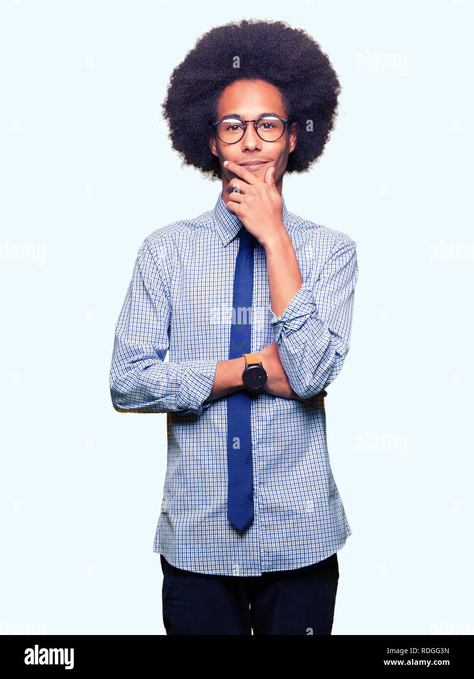 Young african american business man with afro hair wearing glasses looking confident at the camera with smile with crossed arms and hand raised on chi Stock Photo