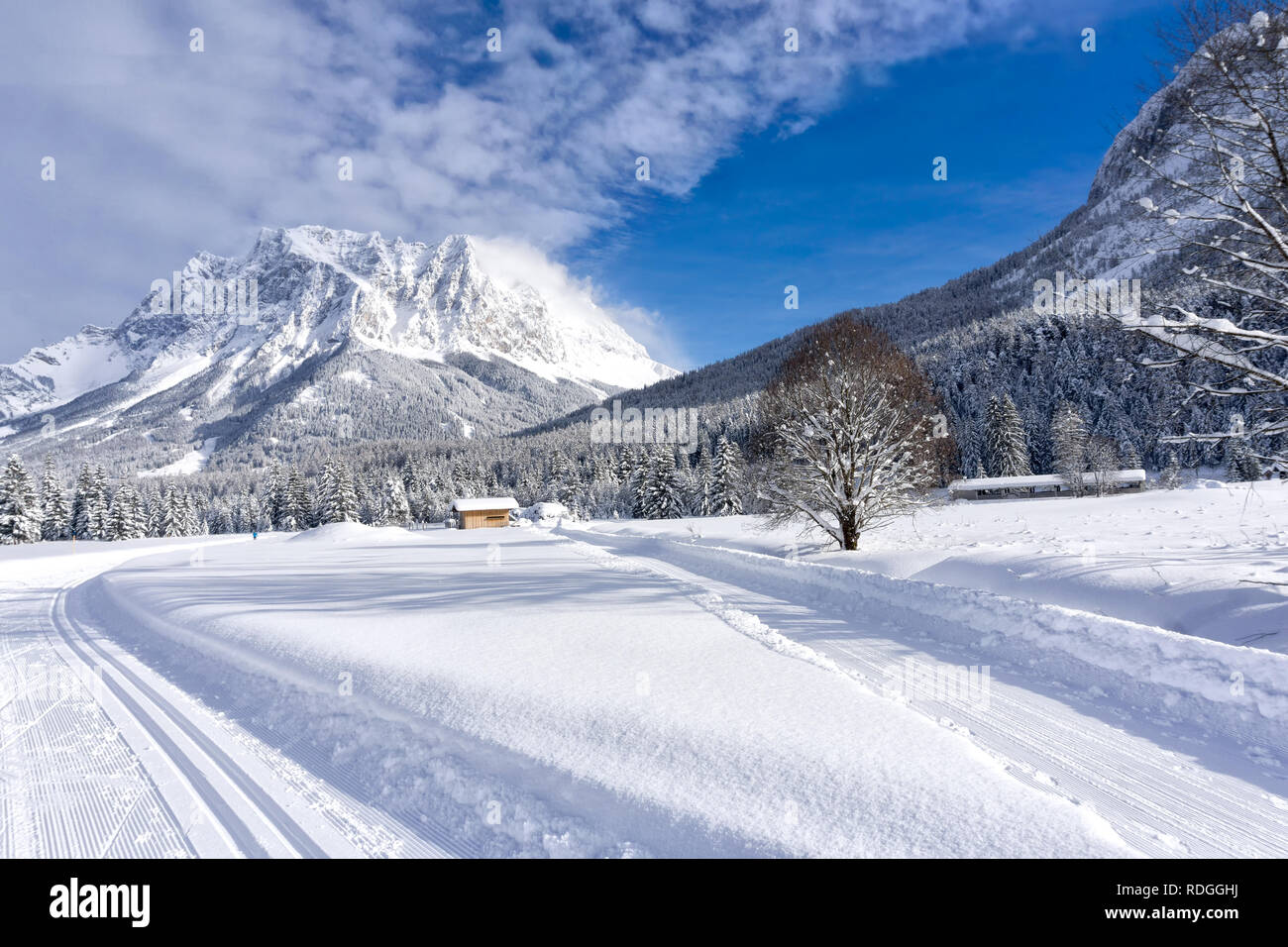 Winter mountain landscape with groomed ski trails and blue sky in sunny day. Ehrwald valley, Tirol, Alps, Austria, Zugspitze Massif  in background. Stock Photo