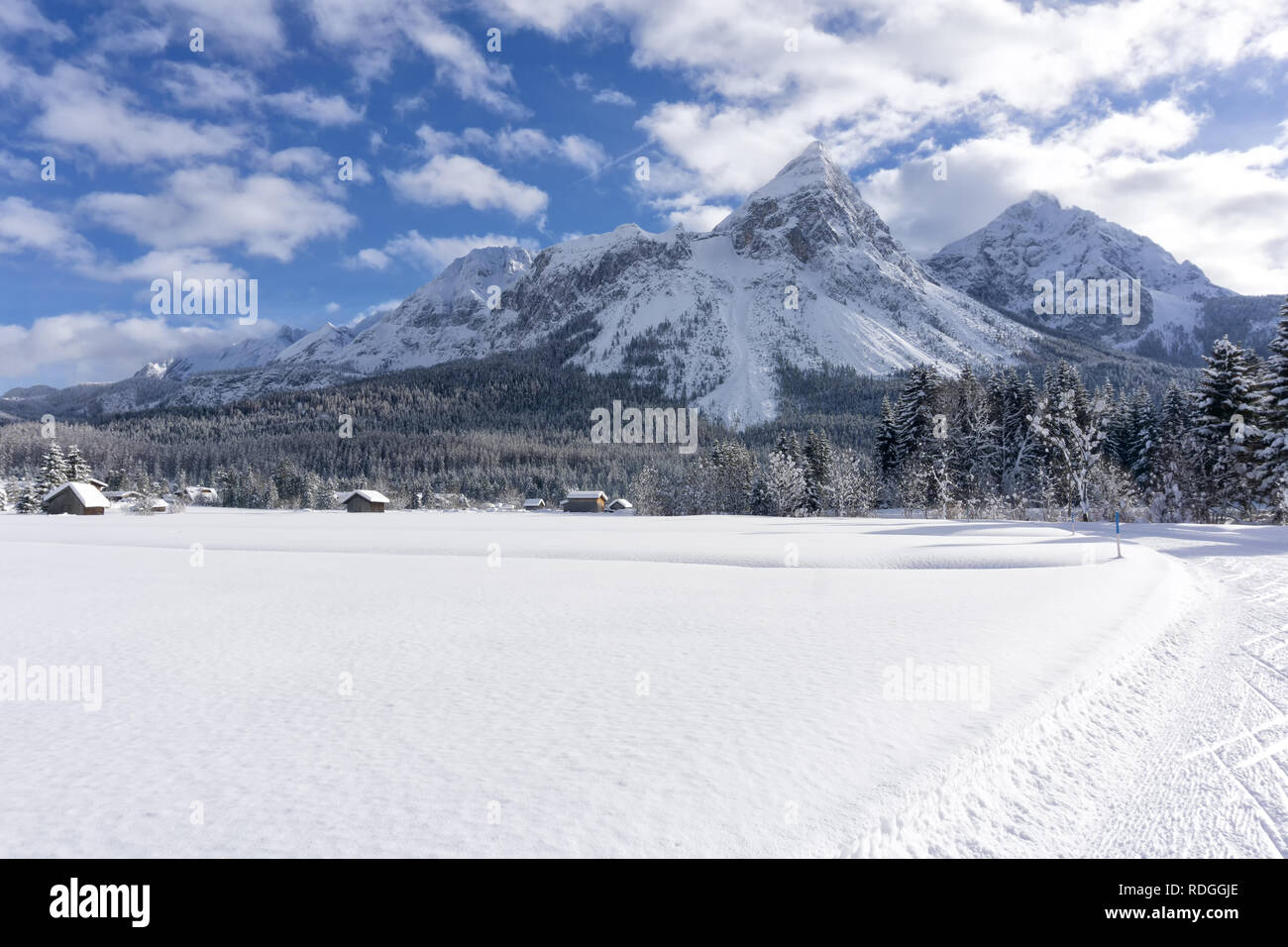 Winter mountain landscape with groomed ski trails and blue sky with white clouds in sunny day. Ehrwald valley, Tirol, Alps, Austria. Stock Photo