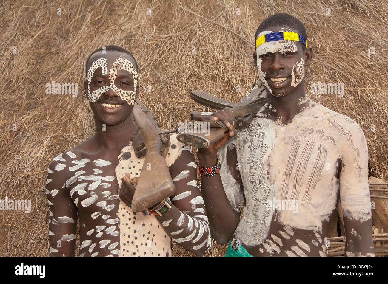 Two Karo warriors with body and facial paintings and a rifle on the shoulder, Omo river valley, Southern Ethiopia, Africa Stock Photo