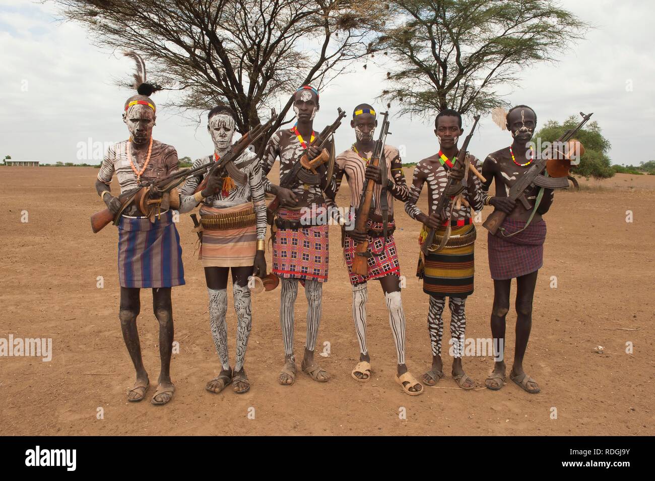 Group of Karo warriors with body and facial paintings holding a rifle over their shoulder, Omo river valley, Southern Ethiopia Stock Photo