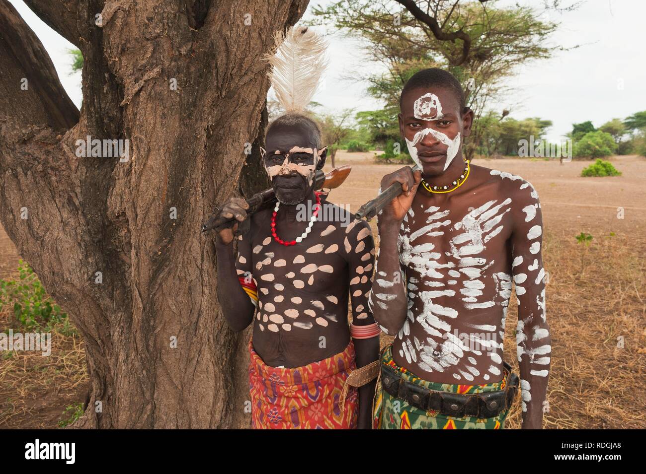 Two Karo warriors with body and facial paintings holding a rifle over their shoulder, Omo river valley, Southern Ethiopia Stock Photo