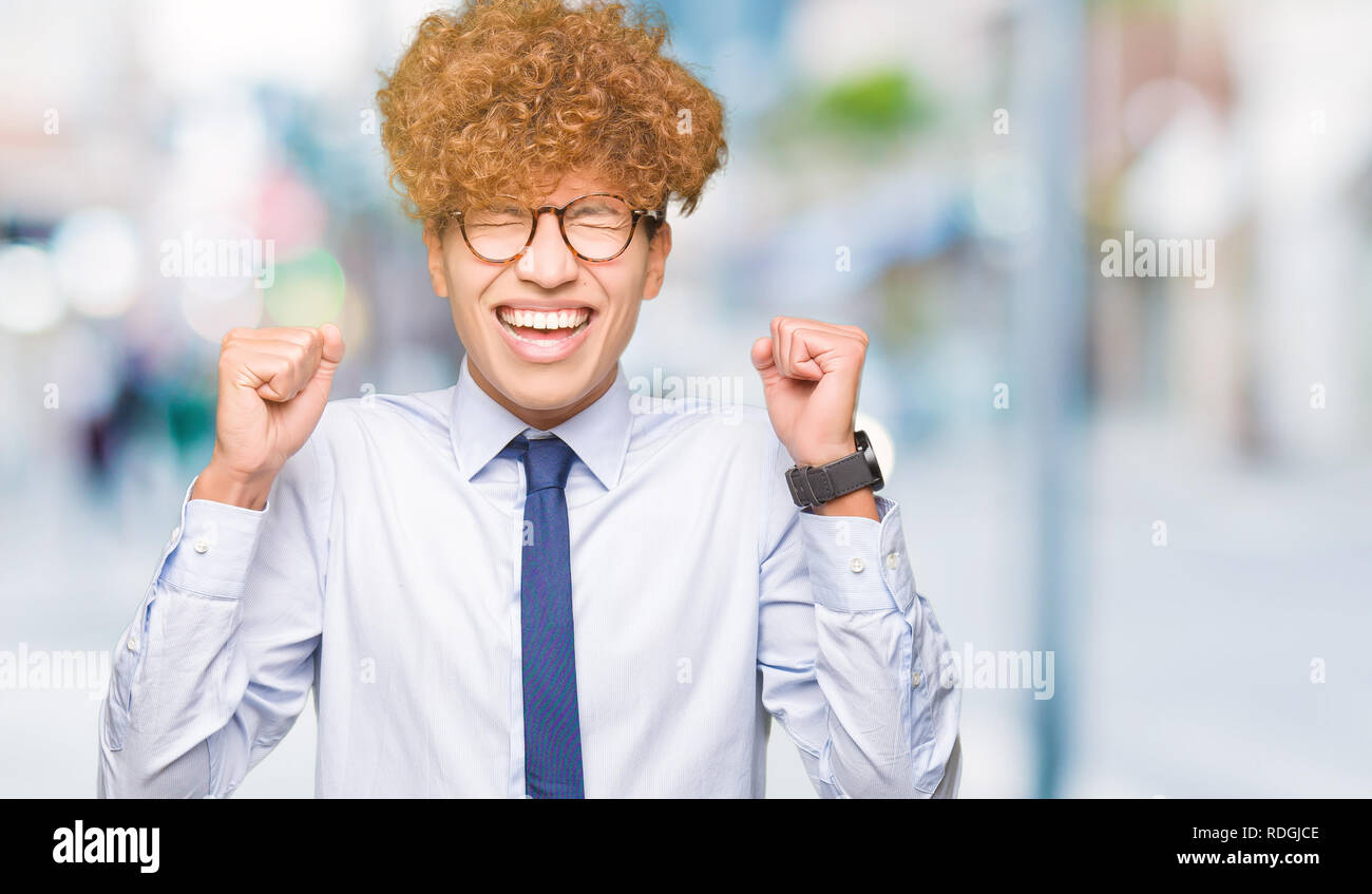 Young handsome business man with afro wearing glasses excited for ...