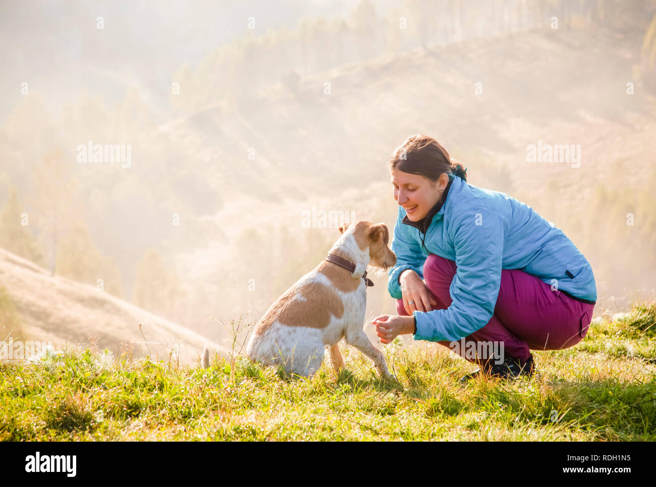 woman playing with her dog in beautiful mountain scenery in spring Stock Photo