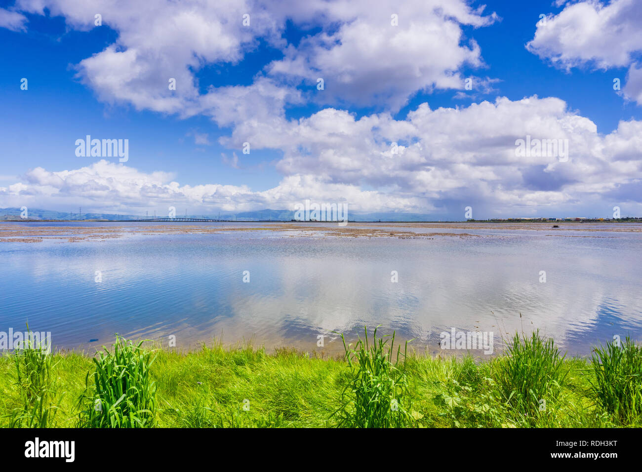 Cloudscape reflected in the ponds; Dumbarton bridge and office buildings in the background; Bedwell Bayfront Park, Menlo Park, San Francisco bay area, Stock Photo
