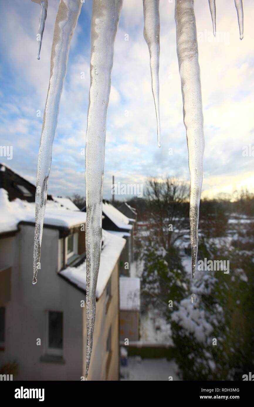 Large icicles hanging from the window of a house, thaw, falling chunks of ice and icicles creating a hazard for pavements, Essen Stock Photo