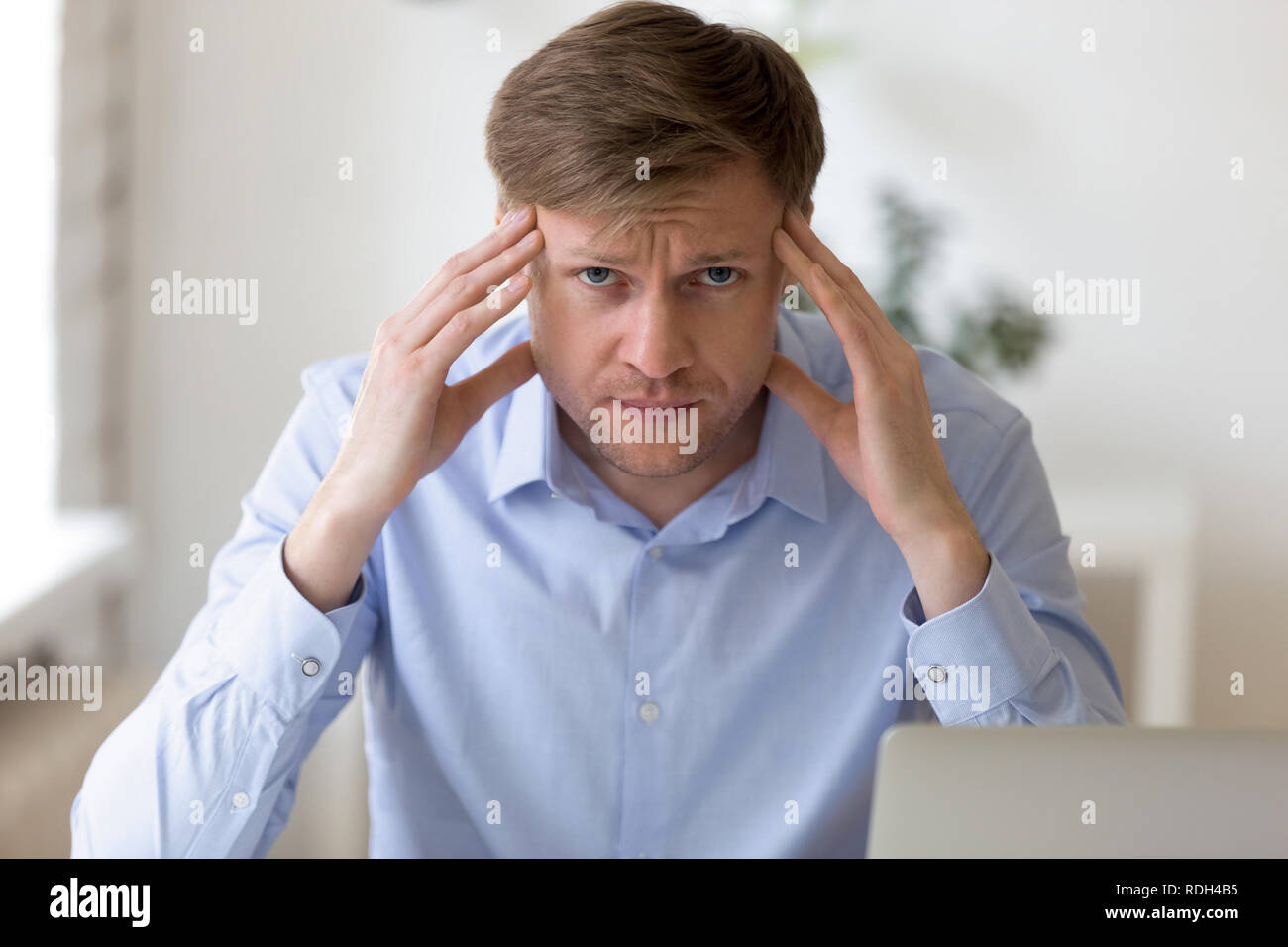 Head shot portrait of thoughtful businessman touching temples Stock Photo