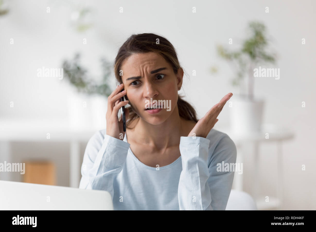 Upset unpleasantly surprised woman making phone call Stock Photo