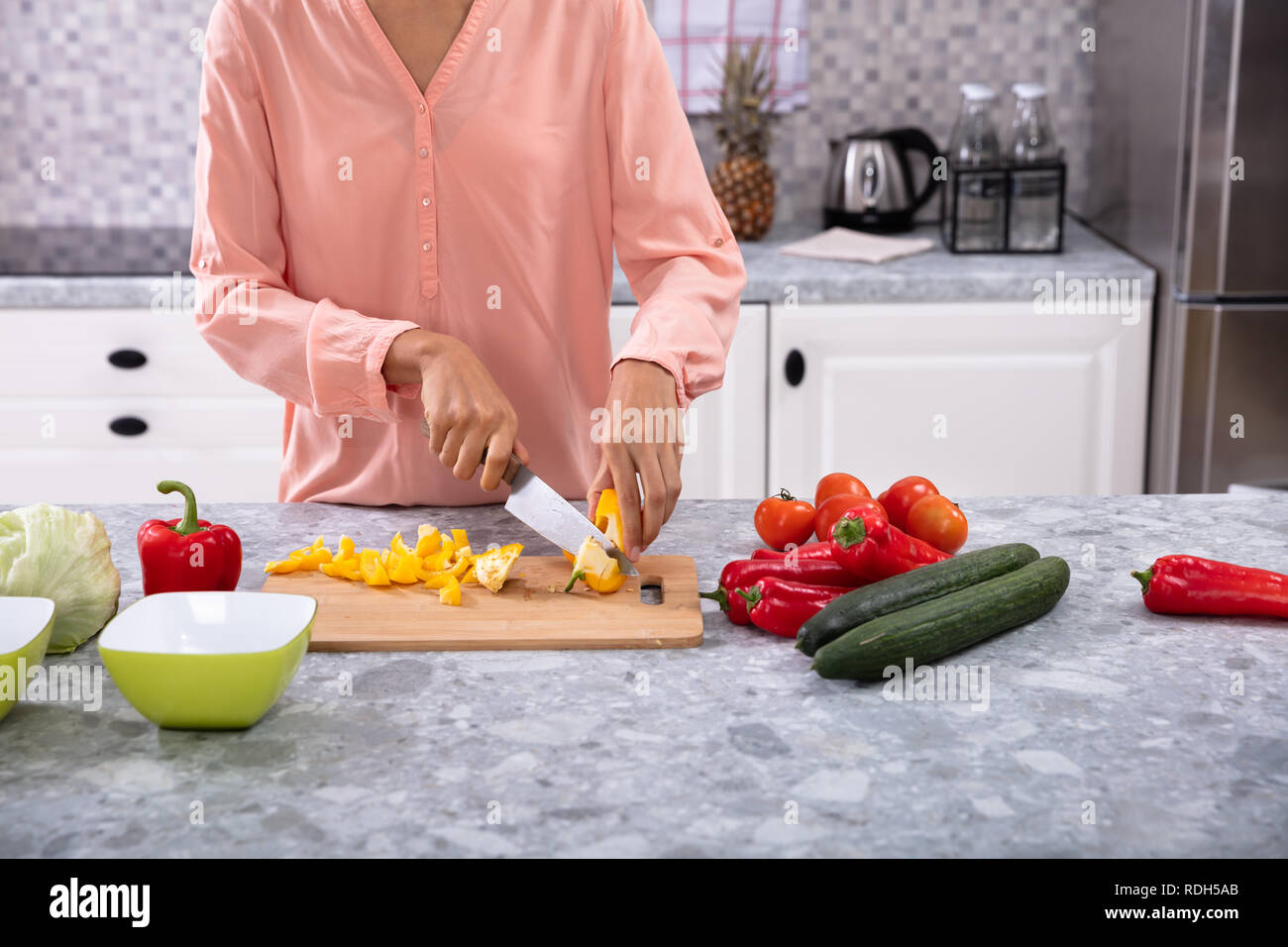 Woman Chopping Bell Pepper On Chopping Board With Knife Over The
