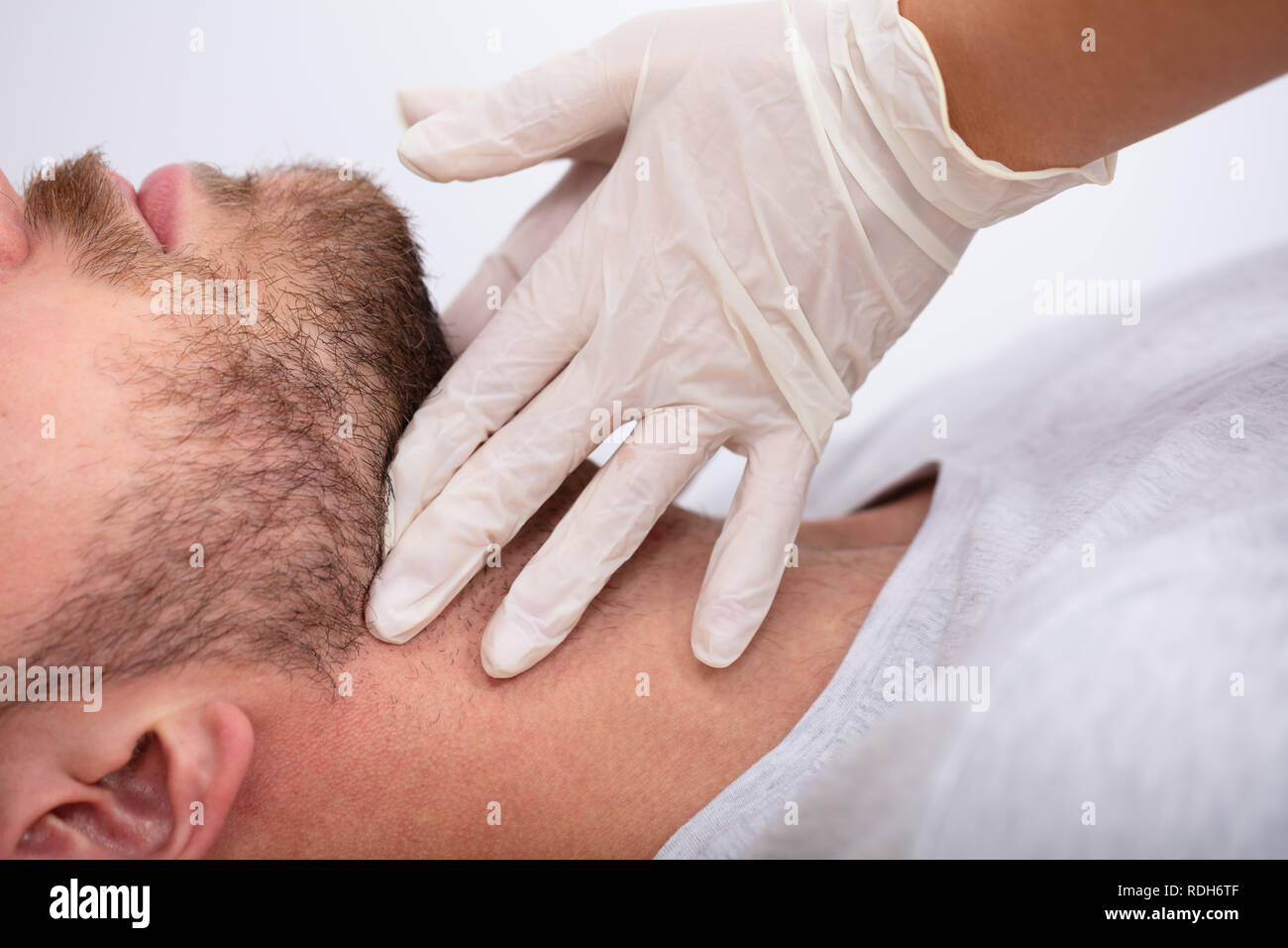 Doctor's Hand Wearing Gloves Performing Physical Exam Palpation Of The Thyroid Gland Stock Photo