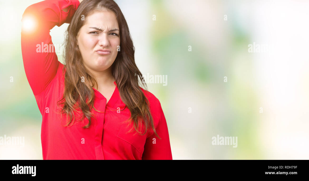 Beautiful plus size young business woman over isolated background confuse and wonder about question. Uncertain with doubt, thinking with hand on head. Stock Photo
