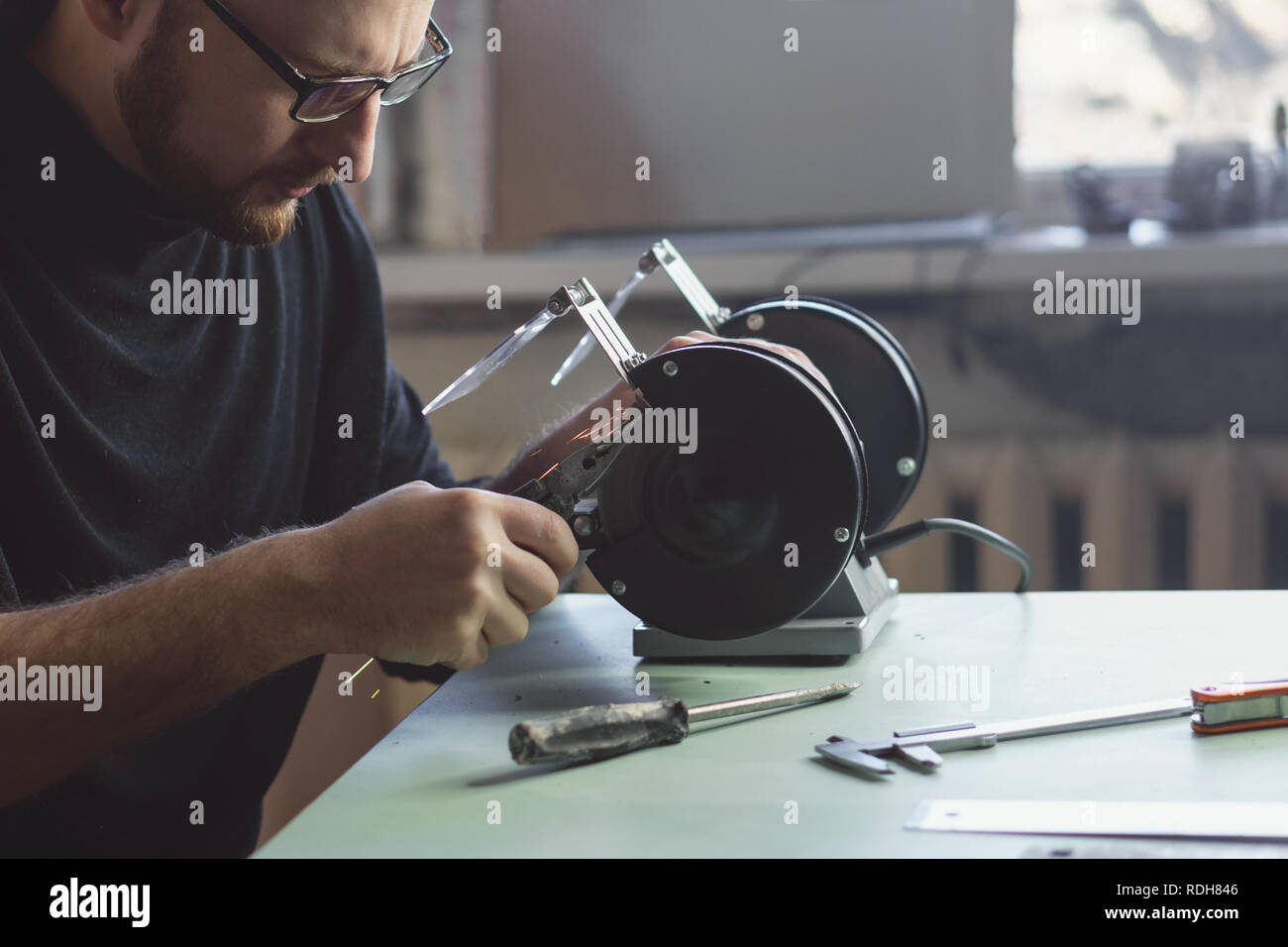 Master works for grinding machine. Man with glasses handles part ...