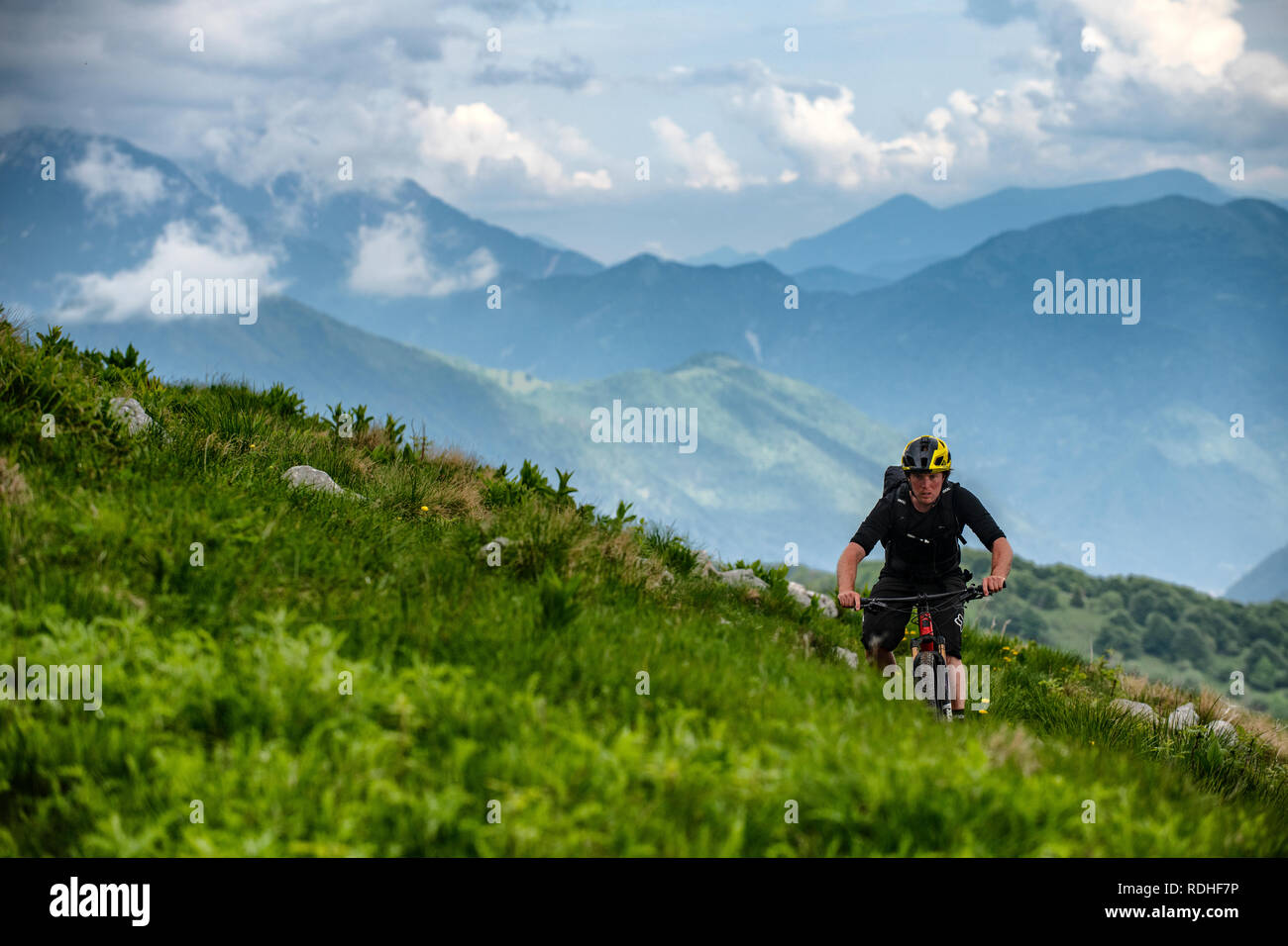A man on a mountain bike rides on Matajur in the Julian Alps on the Slovenia Italy border. Stock Photo