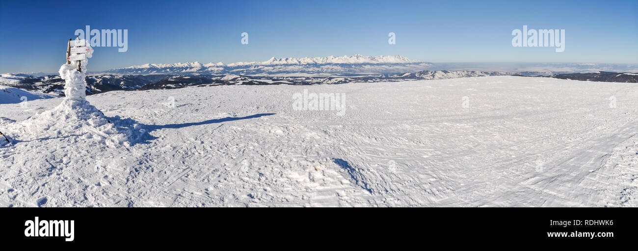 Panorama of Slovakian mountains in winter. Tatra mountains with direction signpost covered by snow. Stock Photo
