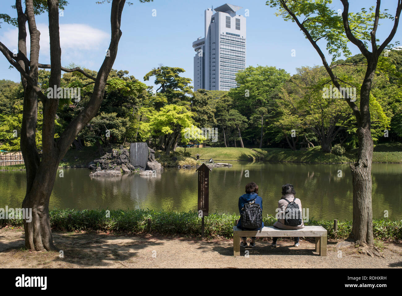 Japan, Honshu Island, Tokyo: women seating on a bench by a pond at Koishikawa-Korakuen Garden, in the district of Koishikawa Stock Photo