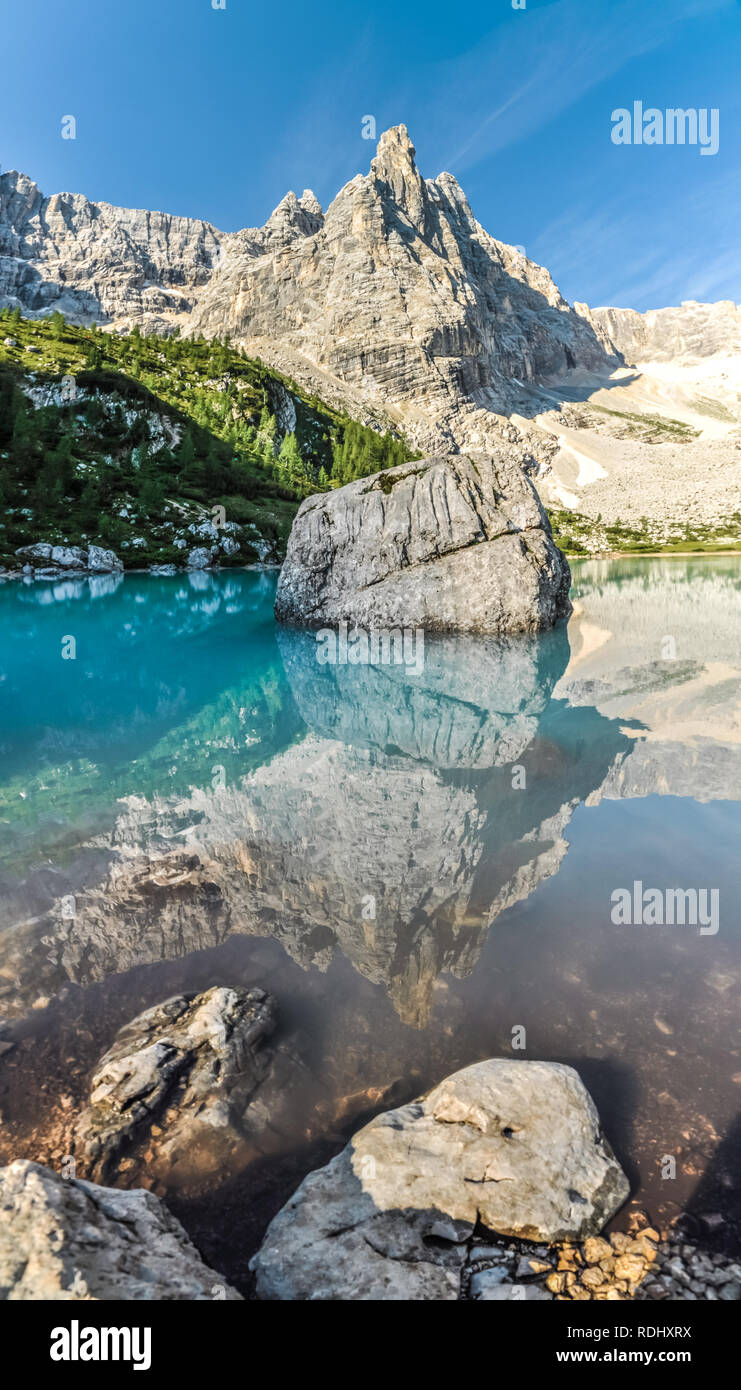 Mirror reflection in crystal clear turquoise Lake Sorapis in Italian Dolomites with sharp rocky mountain peaks. Stock Photo