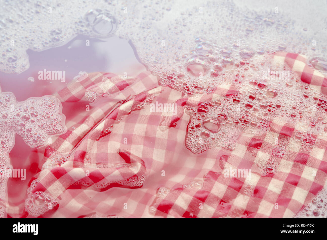 Soak a red white tablecloth before washing Stock Photo