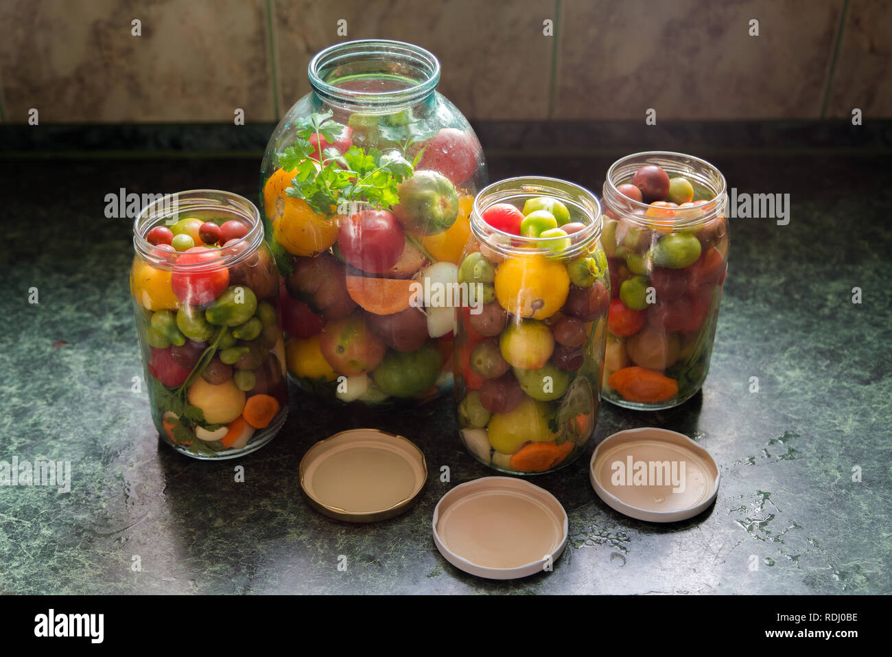 Jars of pickled vegetables. Traditional marinated food - tomatoes, pickles, onions Stock Photo