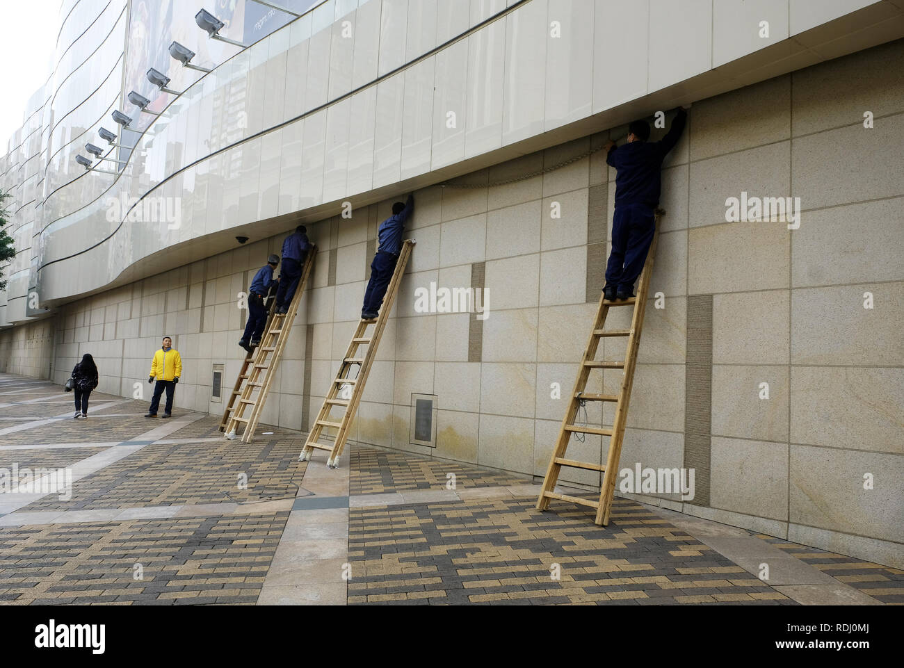 Workmen up ladders in old Macau, China Stock Photo