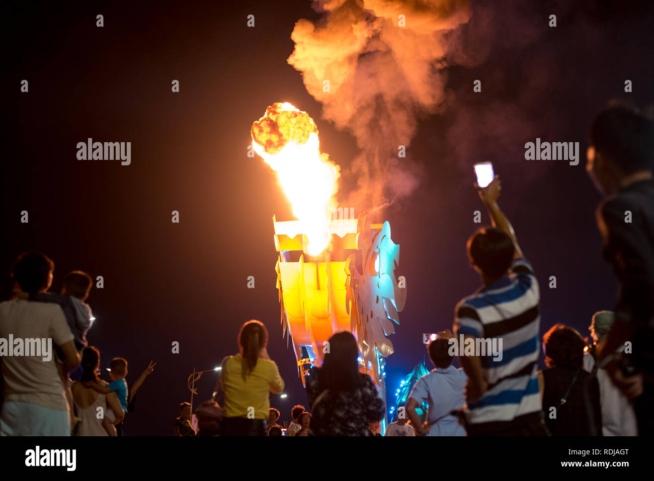 Danang, Vietnam - October 14, 2018: Danang bridge dragon spews fire in the dark of night surrounded by the crowd of spectators. Stock Photo