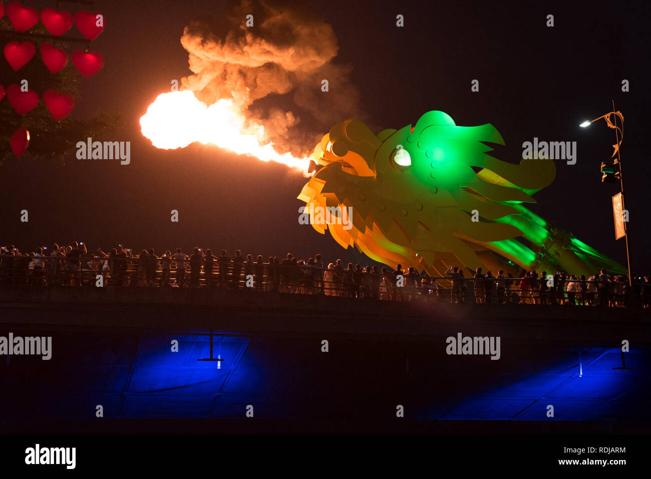 Da Nang, Vietnam - November 11, 2018: the head of the bridge dragon spews smoking fire in the darkness of night in front of the spectators' crowd. Stock Photo