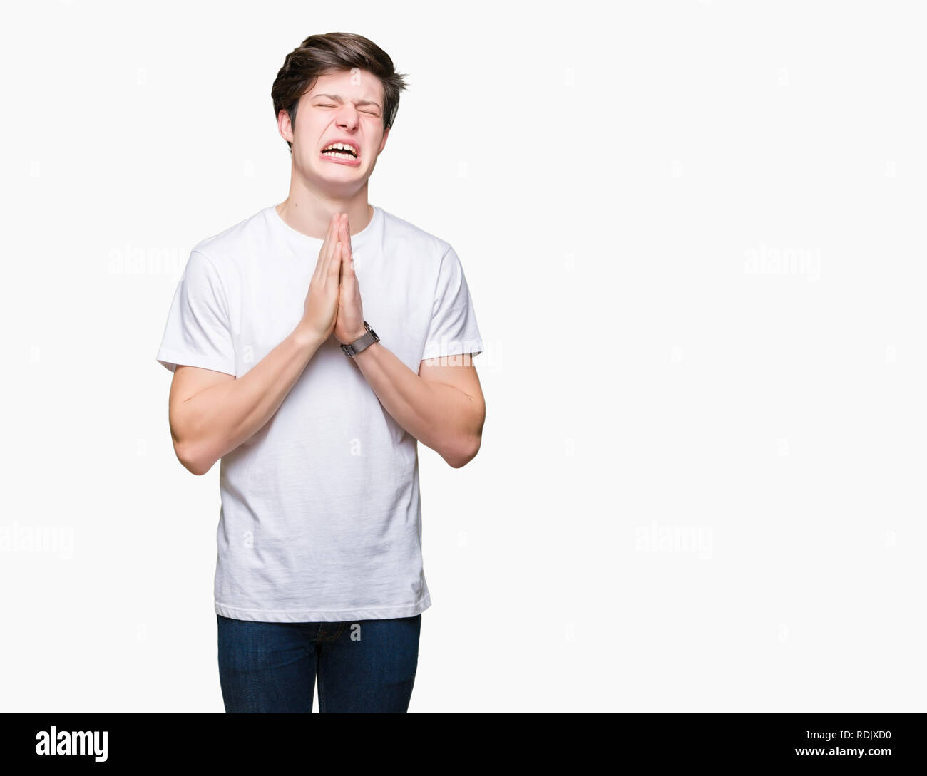 Young handsome man wearing casual white t-shirt over isolated background begging and praying with hands together with hope expression on face very emo Stock Photo