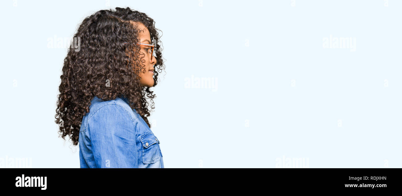 Young Beautiful Woman With Curly Hair Wearing Glasses Looking To