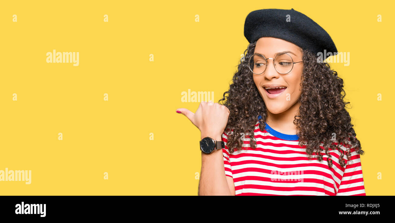 Young beautiful woman with curly hair wearing glasses and fashion beret ...