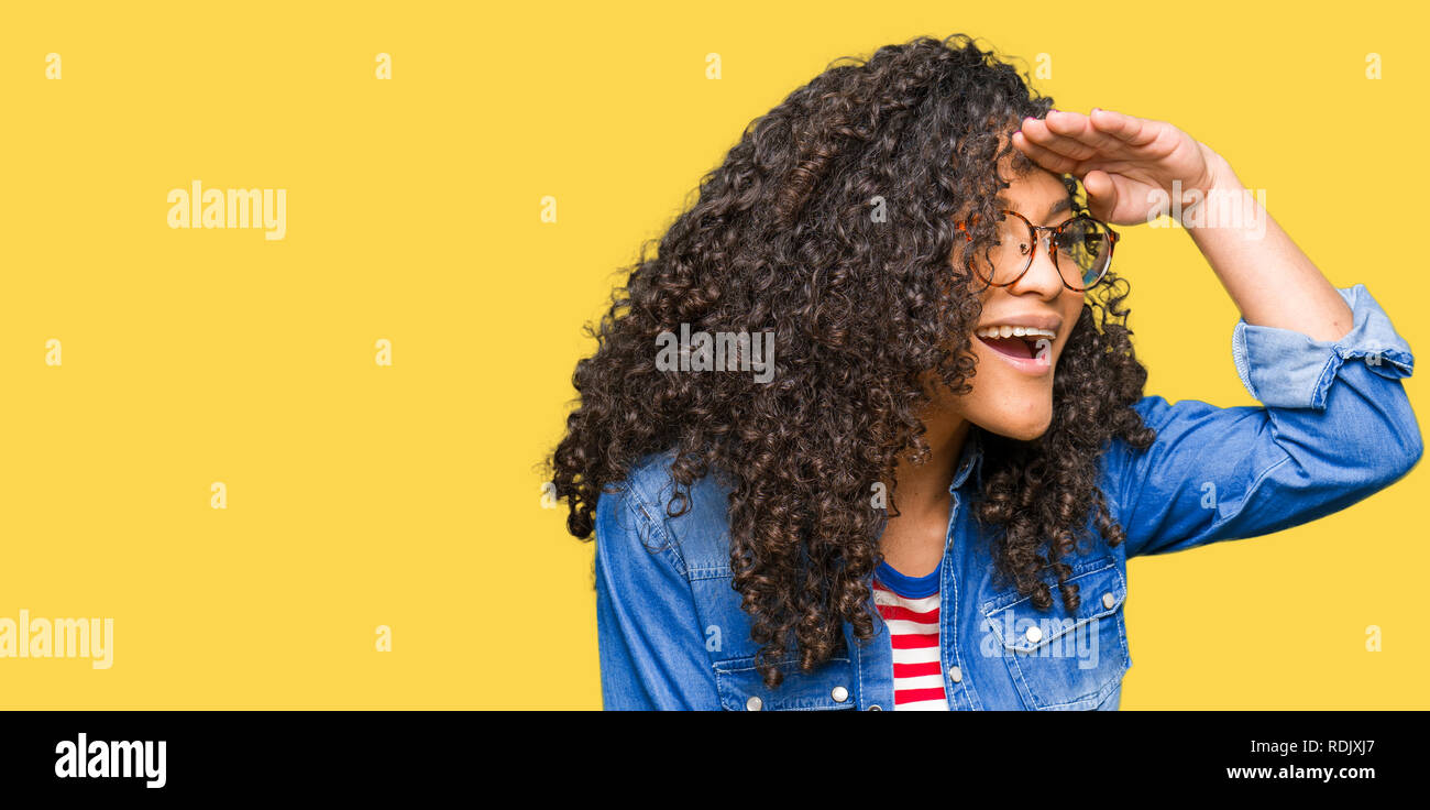 Young beautiful woman with curly hair wearing glasses very happy and ...