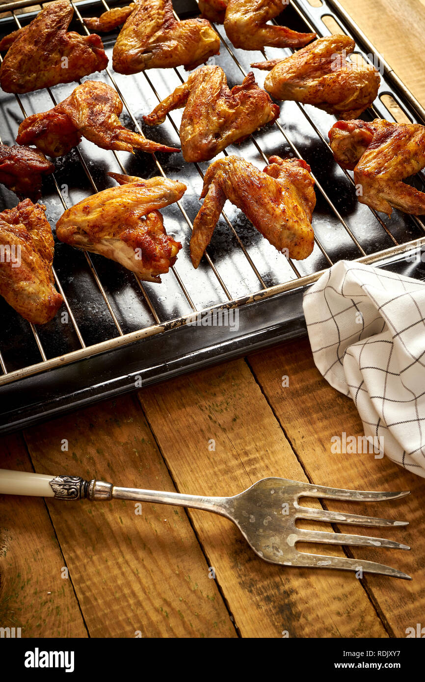 Delicious hot grilled chicken wings on black grill grid with fork and