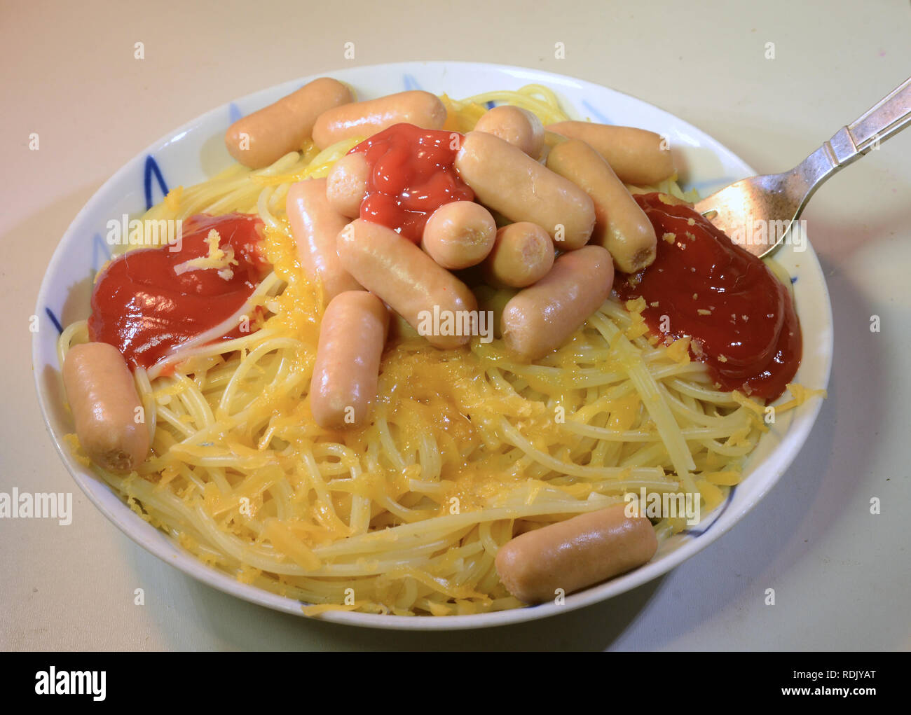 Plate with spaghetti, ketchup shaved cheese and cocktail sausages. Stock Photo