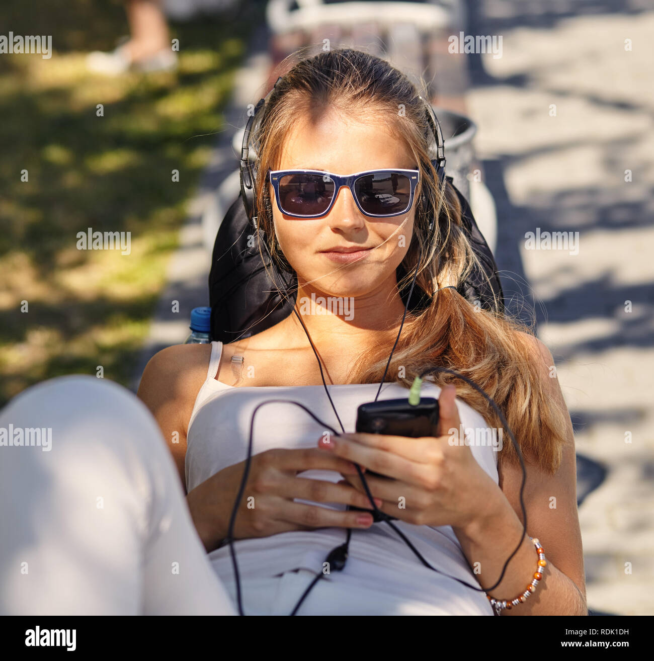 Young curly blonde woman lies, enjoys summer day, bloggs and chats via
