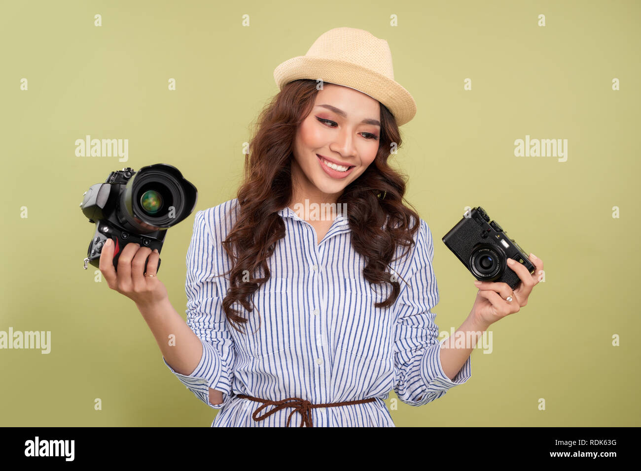 Young woman comparing professional and compact cameras on a solid background Stock Photo