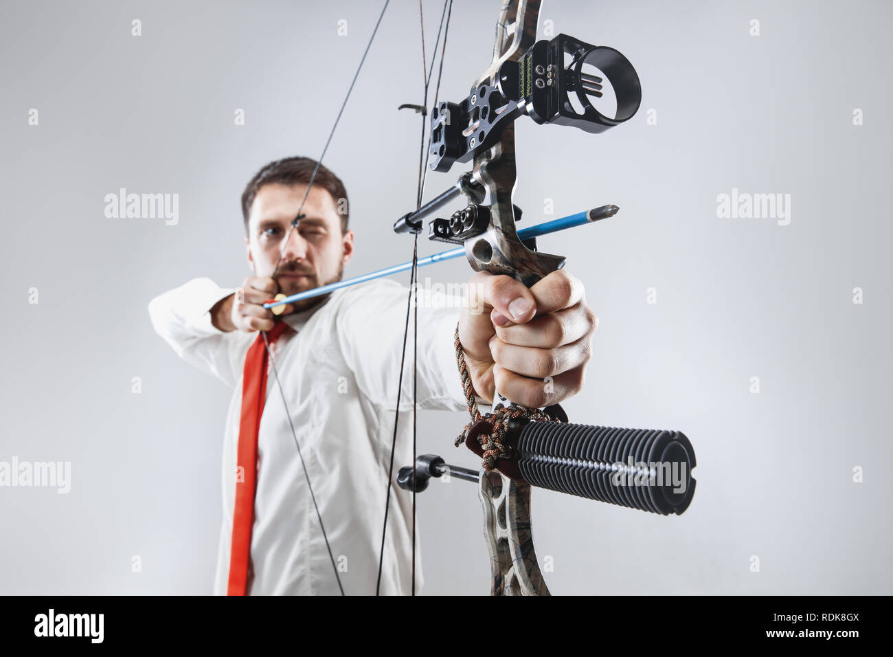 Businessman aiming at target with bow and arrow, isolated on gray studio background. The business, goal, challenge, competition, achievement concept Stock Photo