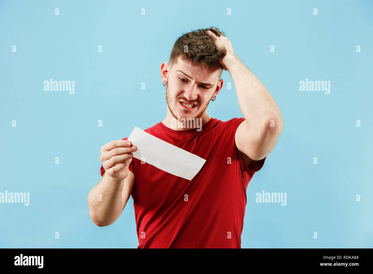 Young boy with a surprised unhappy failure expression bet slip on blue ...