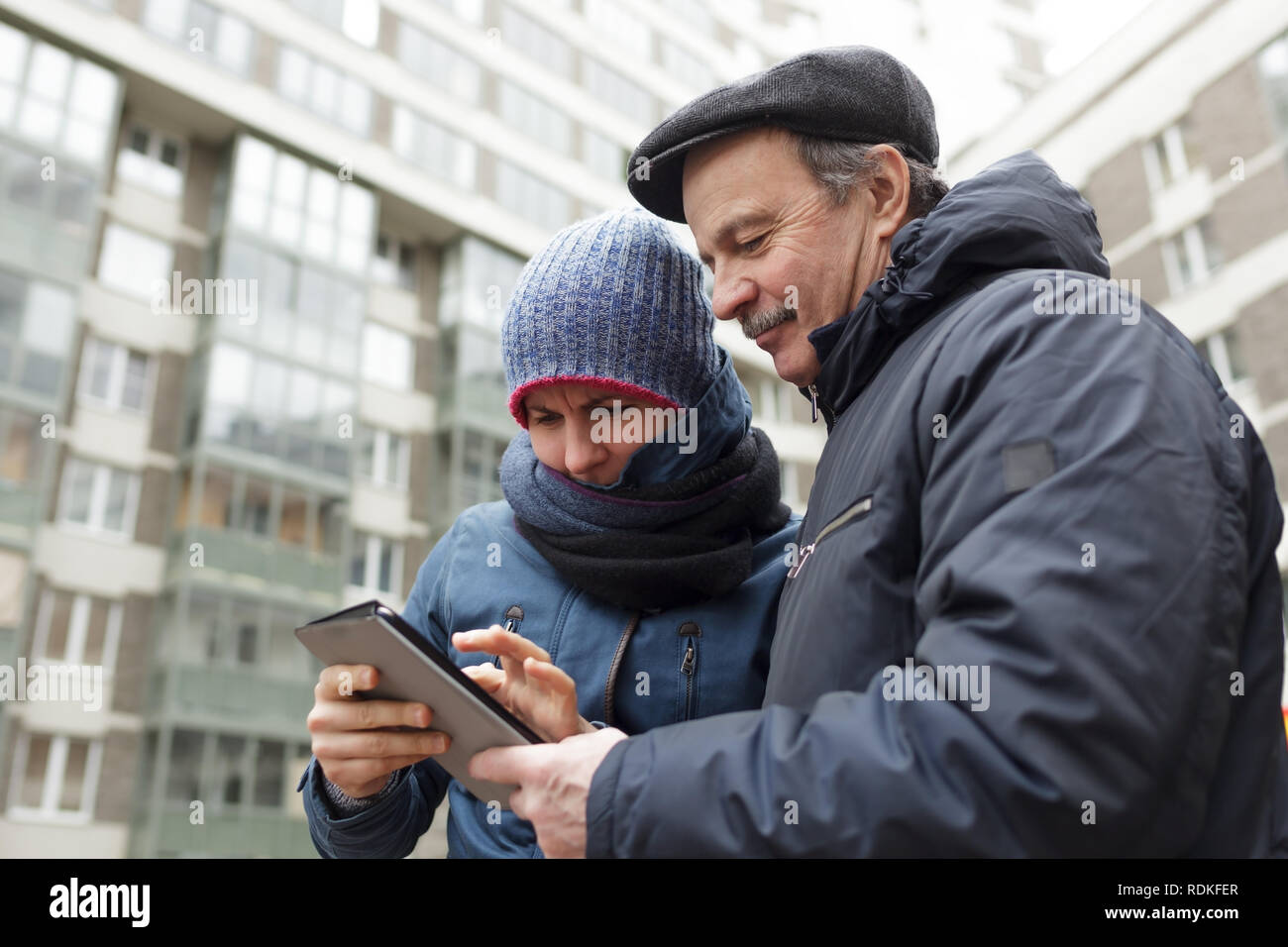 Girl and her father with a tablet in hands looking for right way in city. Stock Photo