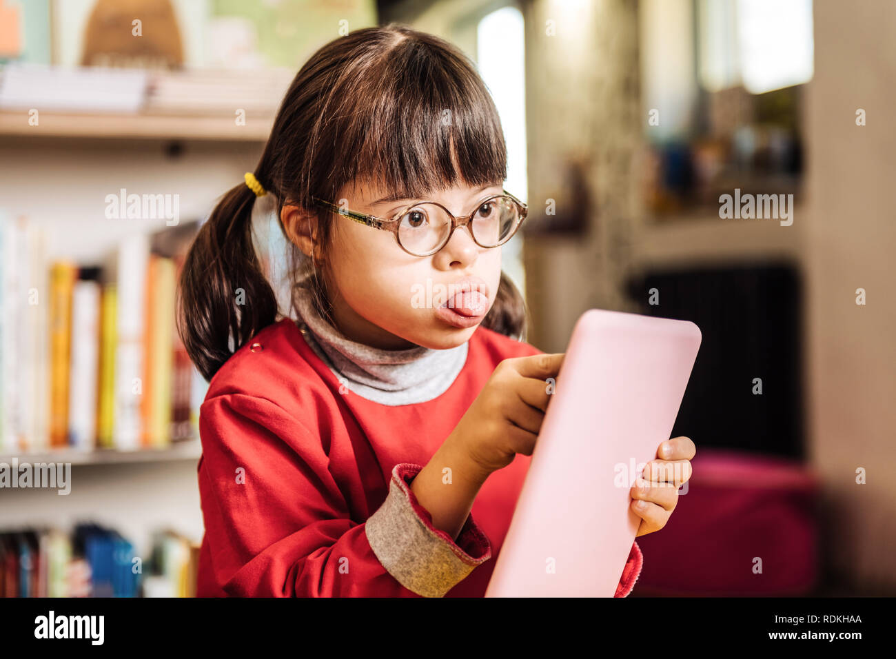 Sunny girl showing her tongue feeling involved in drawing Stock Photo