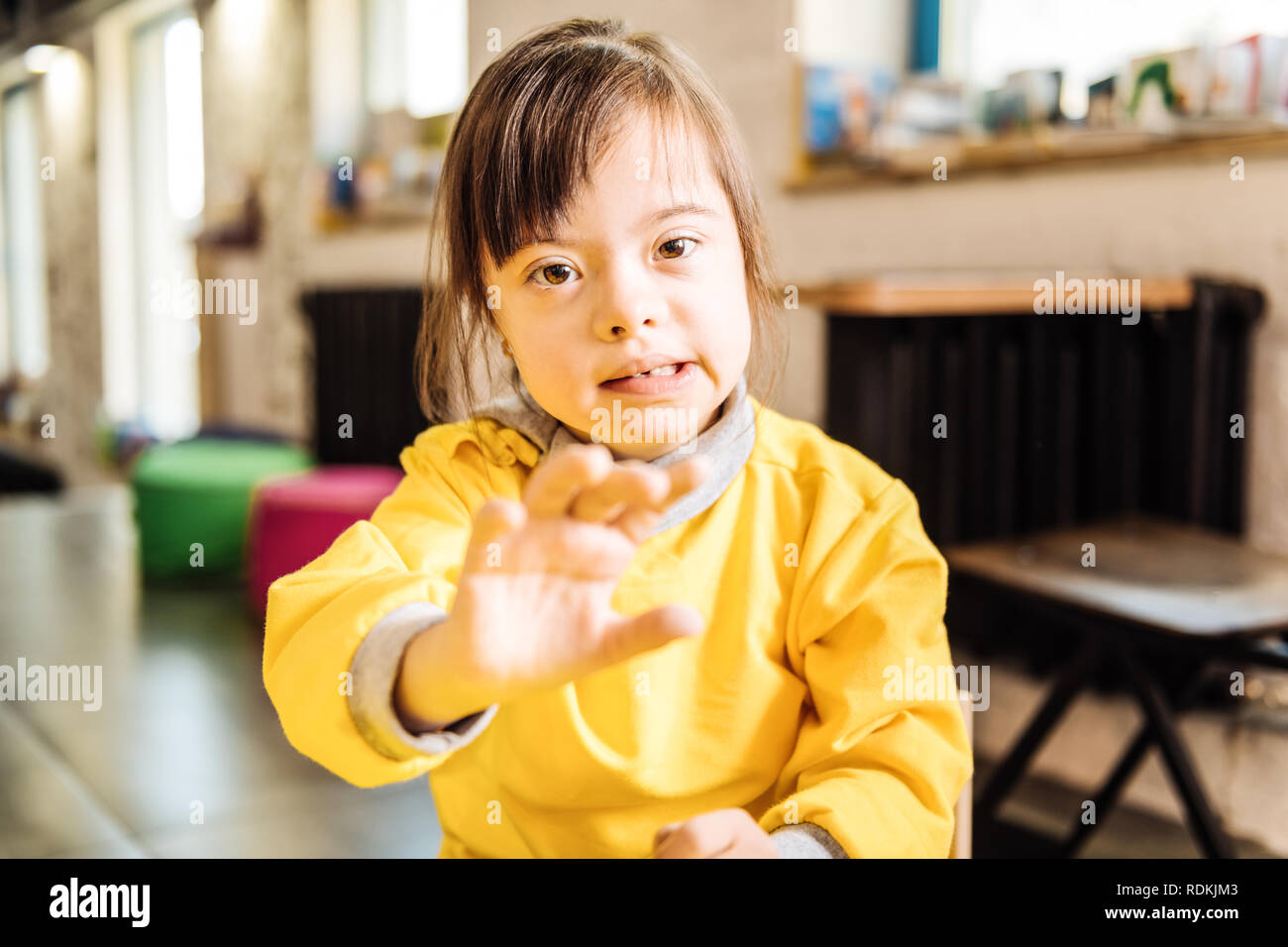 Close up of darkhaired child with Down syndrome sitting near window