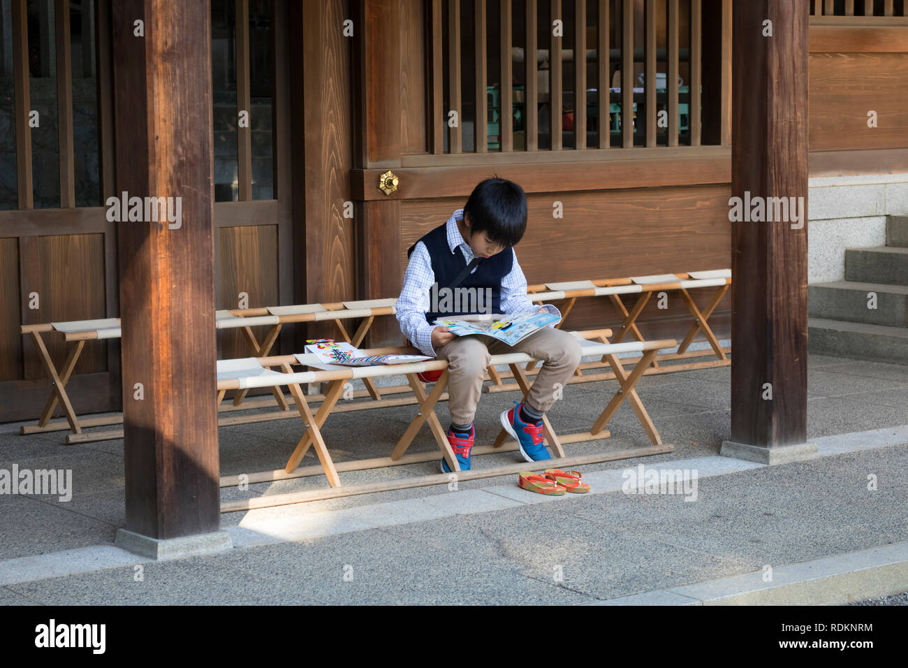 Kumamoto, Japan - November 11, 2018: Little boy is reading a book in front of Izumi shrine in Suizenji Garden, Suizenji Jōjuen Stock Photo