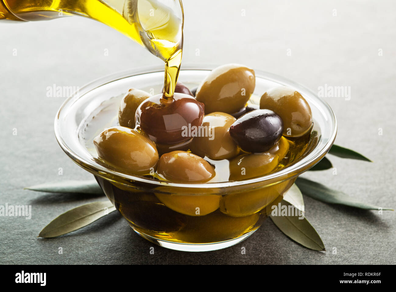 Organic olive oil. Bottle of Extra virgin oil pouring in to glass bowl ...