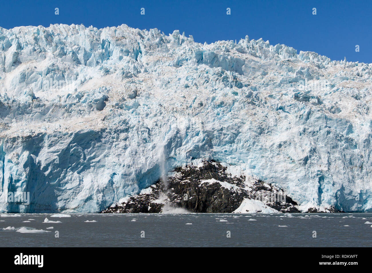 Boat Tours in Kenai Fjords National Park allow tourists to watch and wait for glaciers to calf, dropping huge chunks of ice into the Alaskan ocean Stock Photo