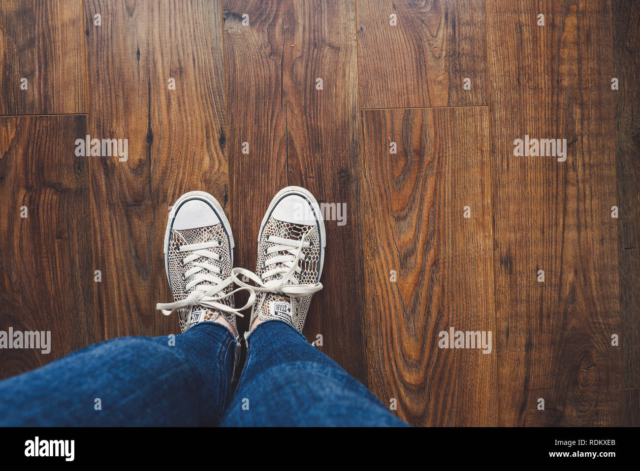 Converse all star shoes / trainers with an animal print, photographed against wooden floor Stock Photo