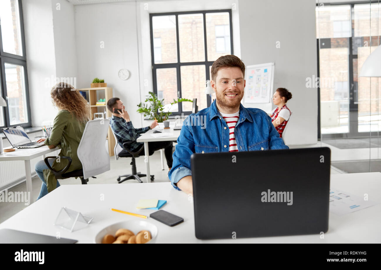smiling creative man with laptop working at office Stock Photo - Alamy