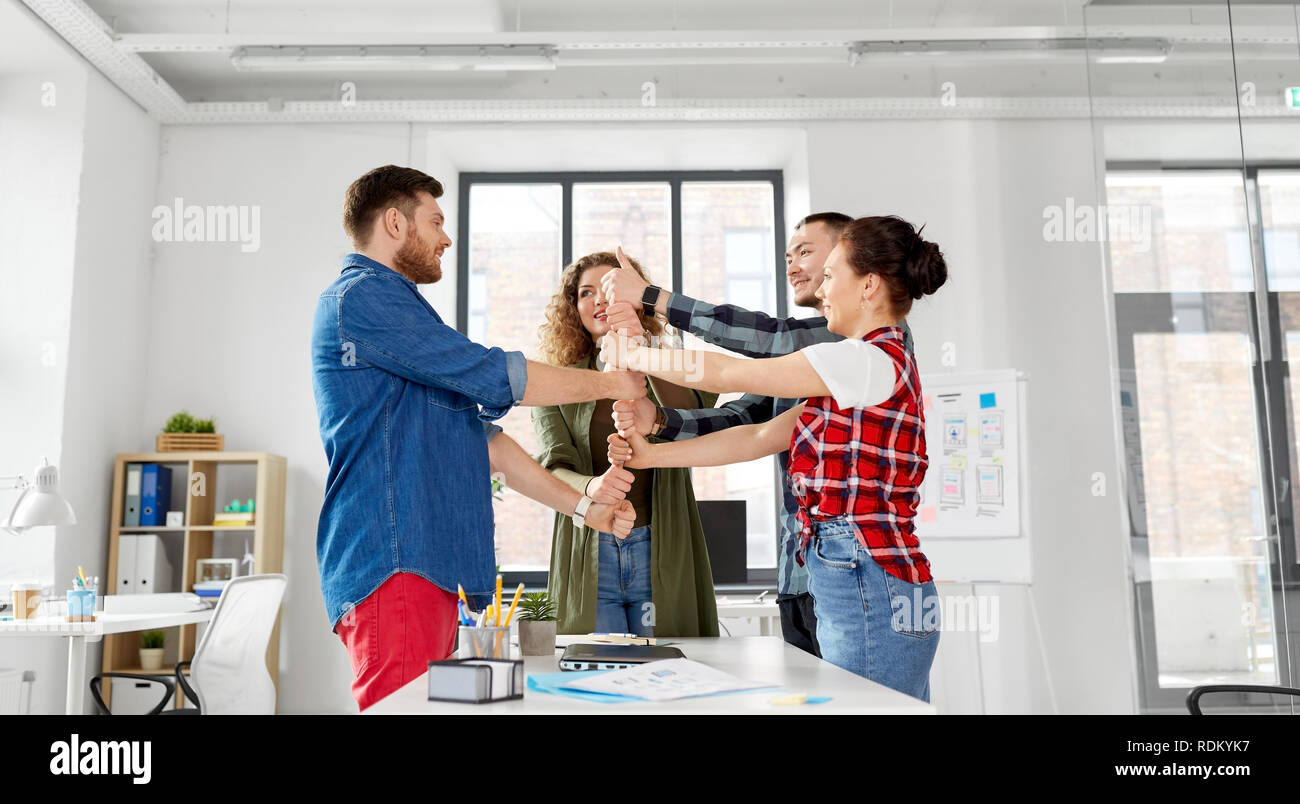 happy creative team showing thumbs up at office Stock Photo - Alamy