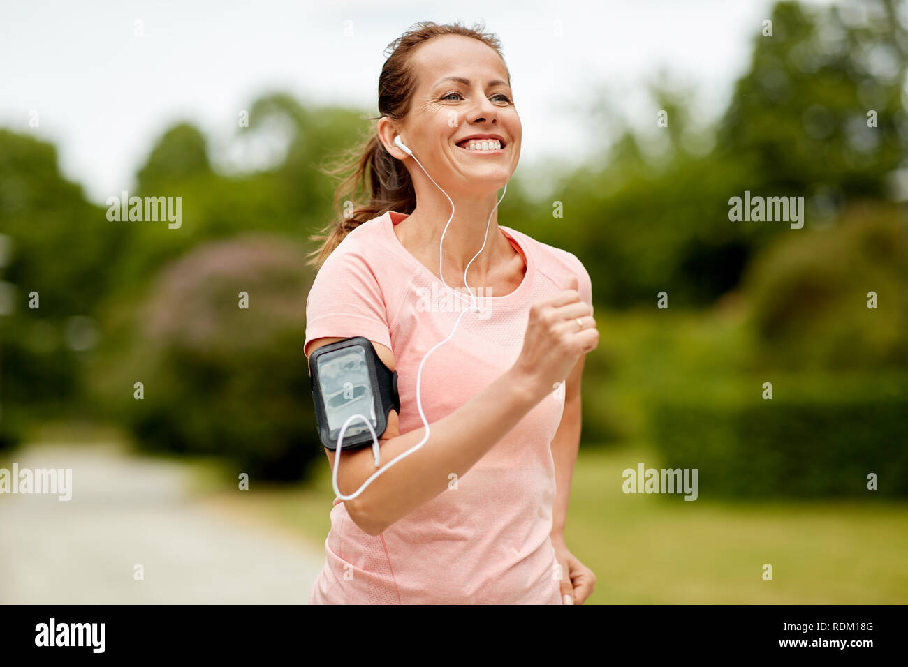 woman with earphones add armband jogging at park Stock Photo