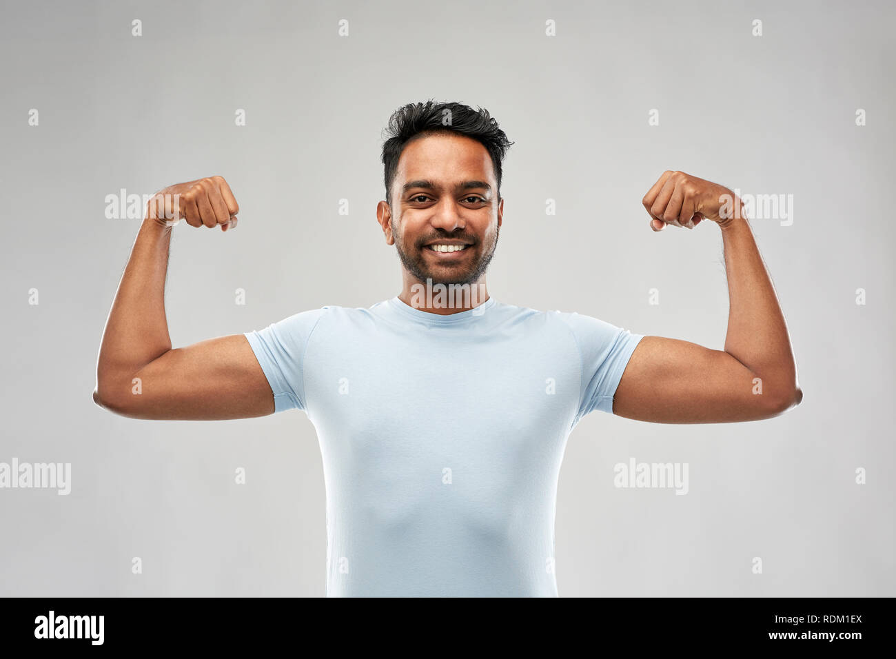 indian man showing biceps over grey background Stock Photo