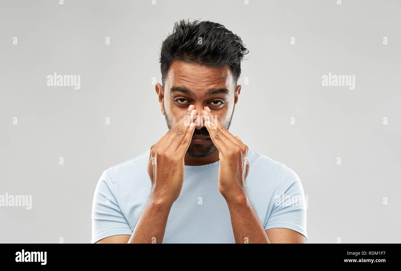 indian man rubbing nose Stock Photo
