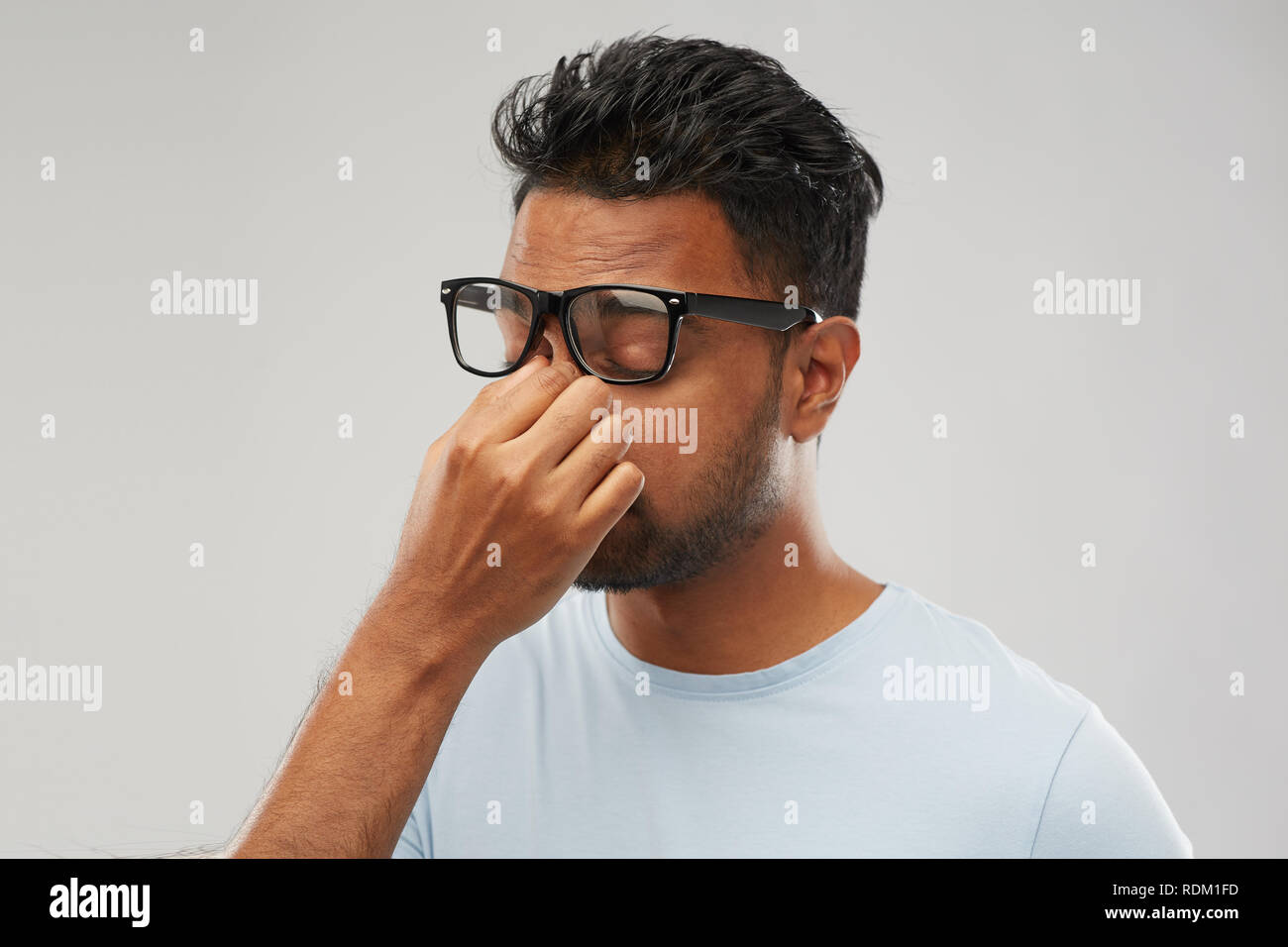 tired indian man in glasses rubbing nose bridge Stock Photo