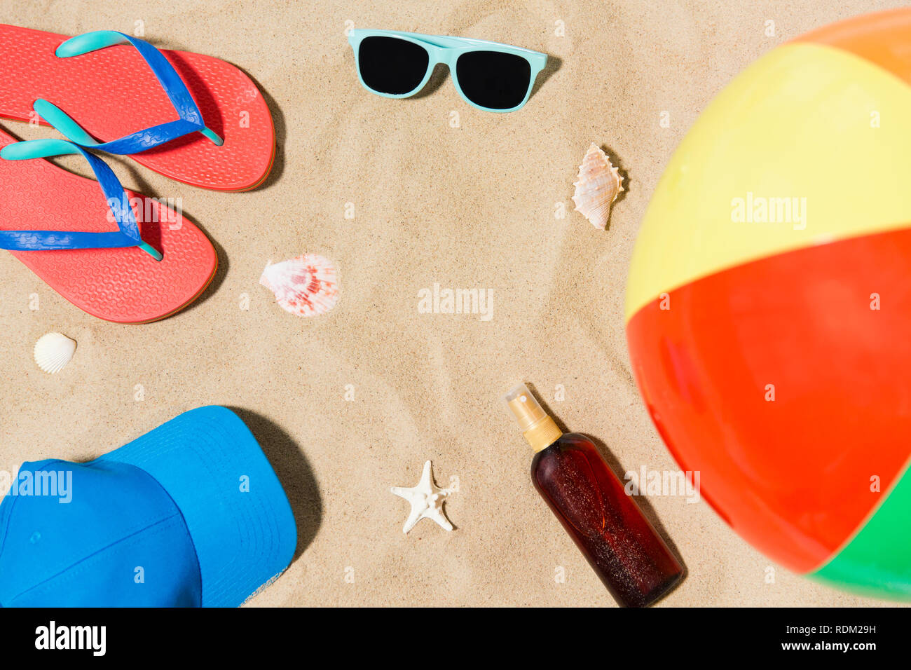 cap, flip flops and shades and beach ball on sand Stock Photo - Alamy