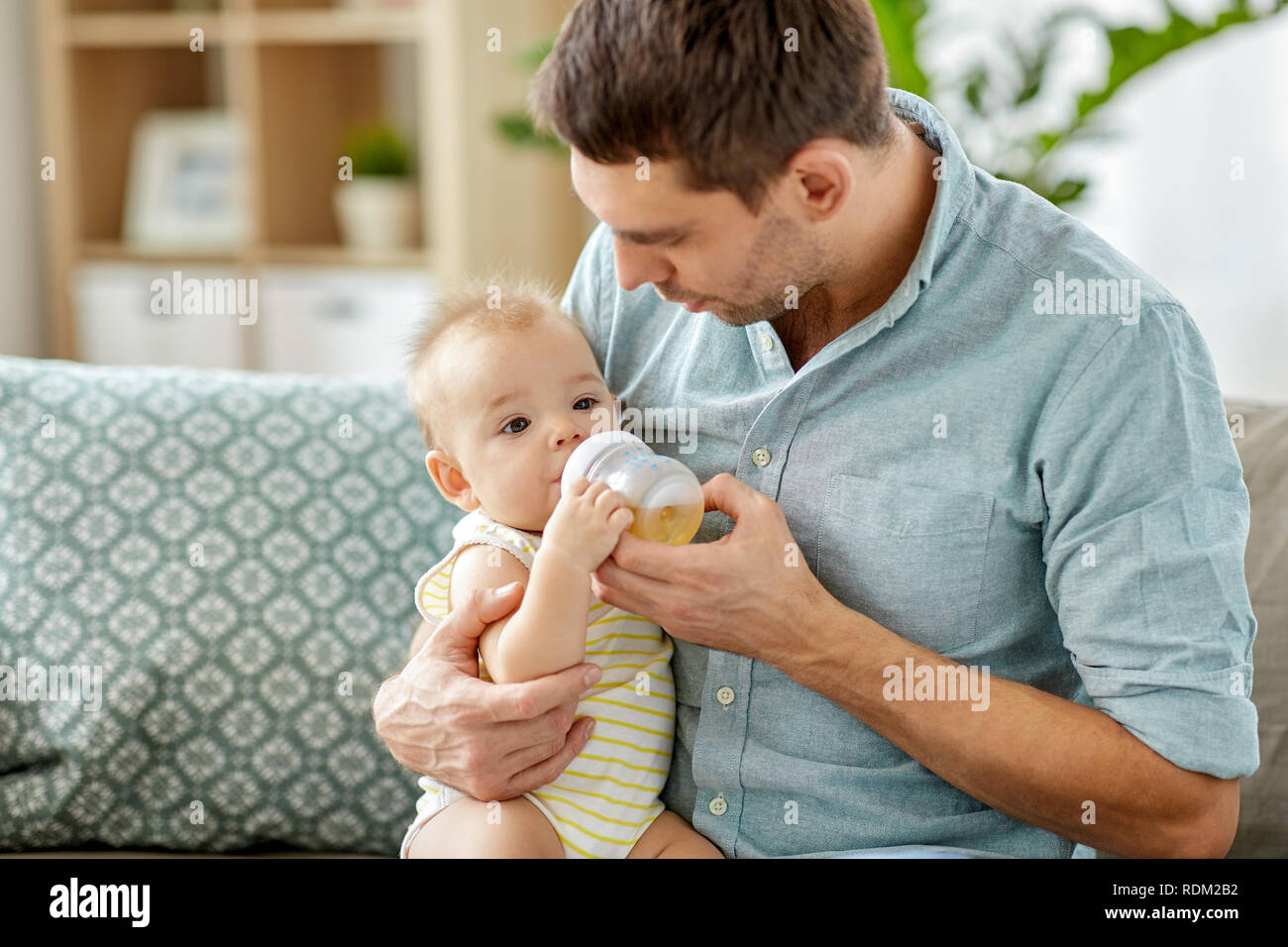father and baby drinking from bottle at home Stock Photo
